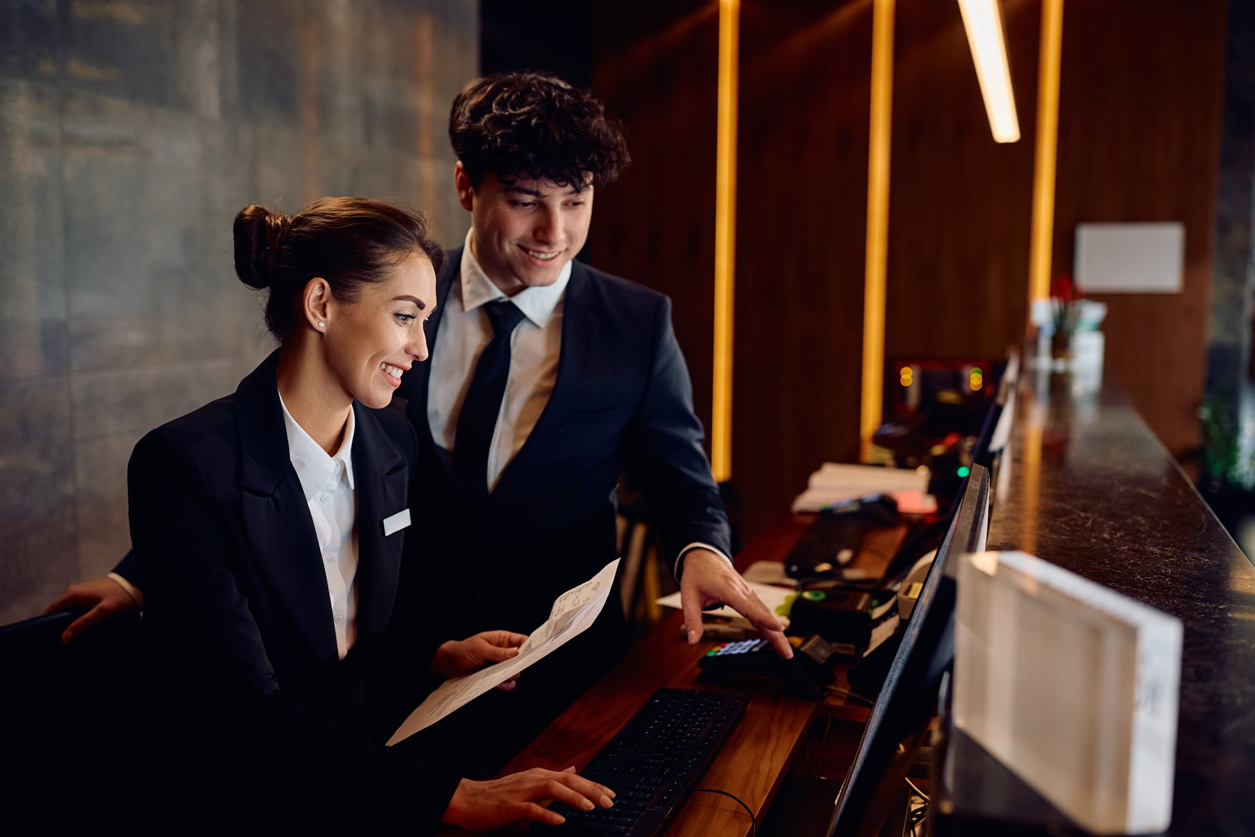 Hotelteam an der Rezeption prueft Buchungen im System - mehr Direktbuchungen ueber die eigene Buchungsstrecke statt ueber Booking