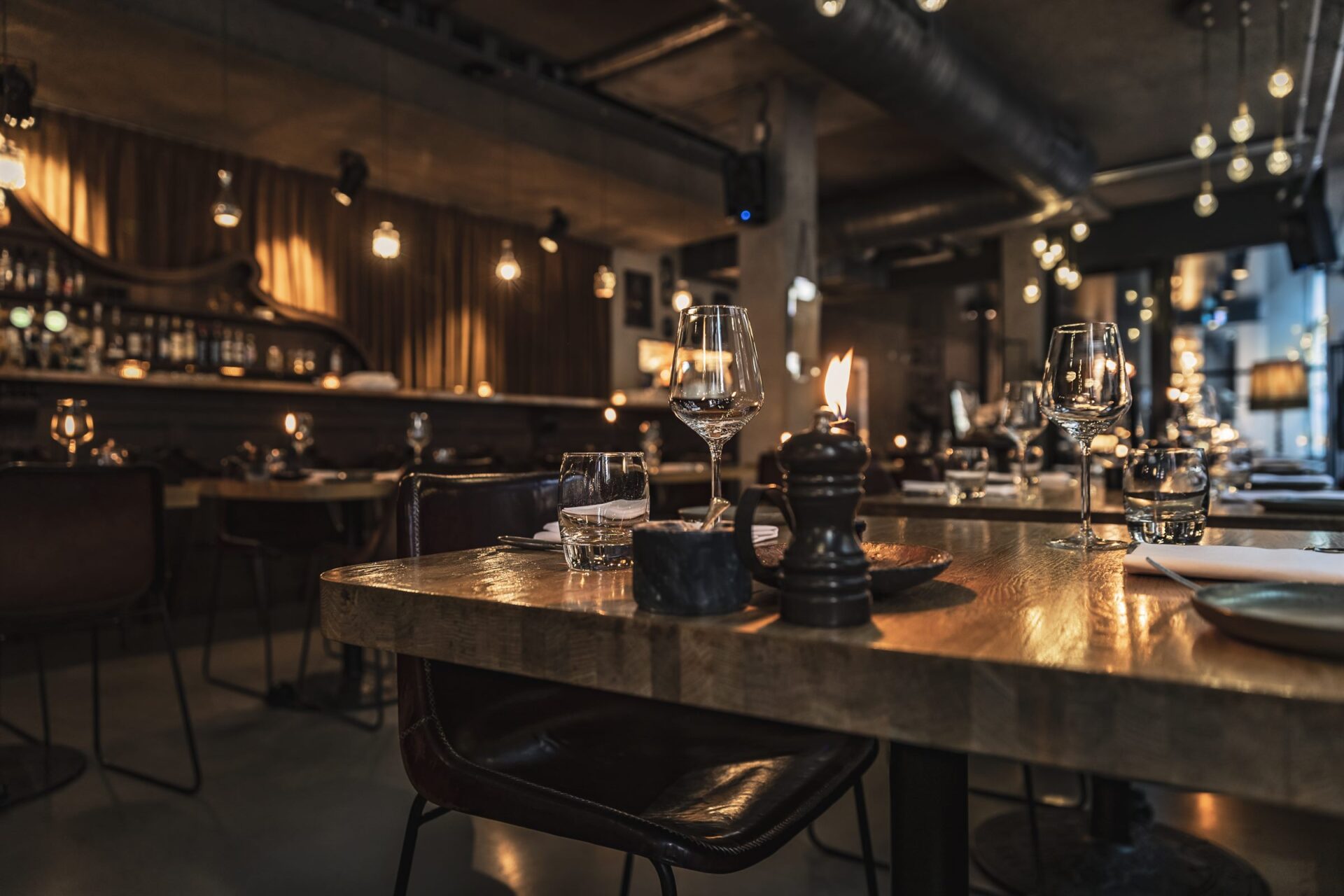 Gedeckter Tisch in einem Restaurant am Abend, im Hintergrund die Bar