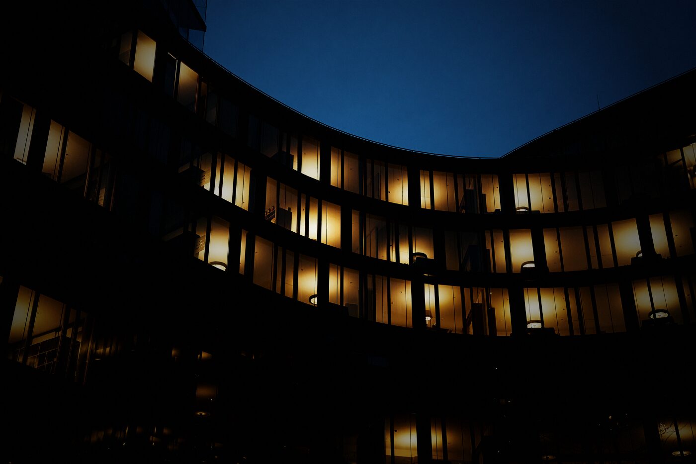 Hotelfassade bei Nacht mit warm beleuchteten Zimmerfenstern