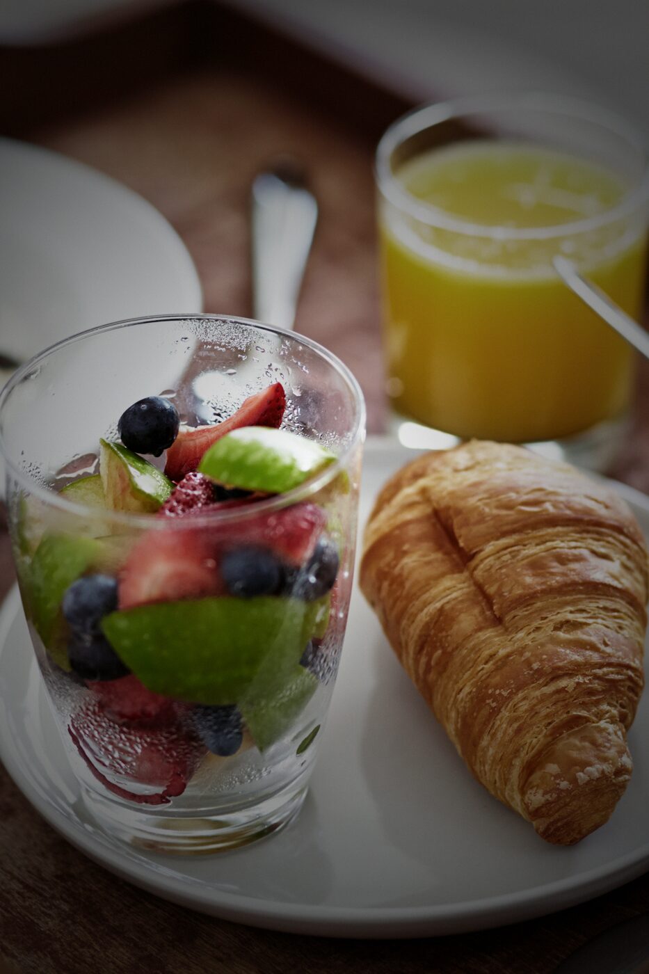 Frühstückstablett mit Croissant, Obst und Orangensaft im Hotelzimmer