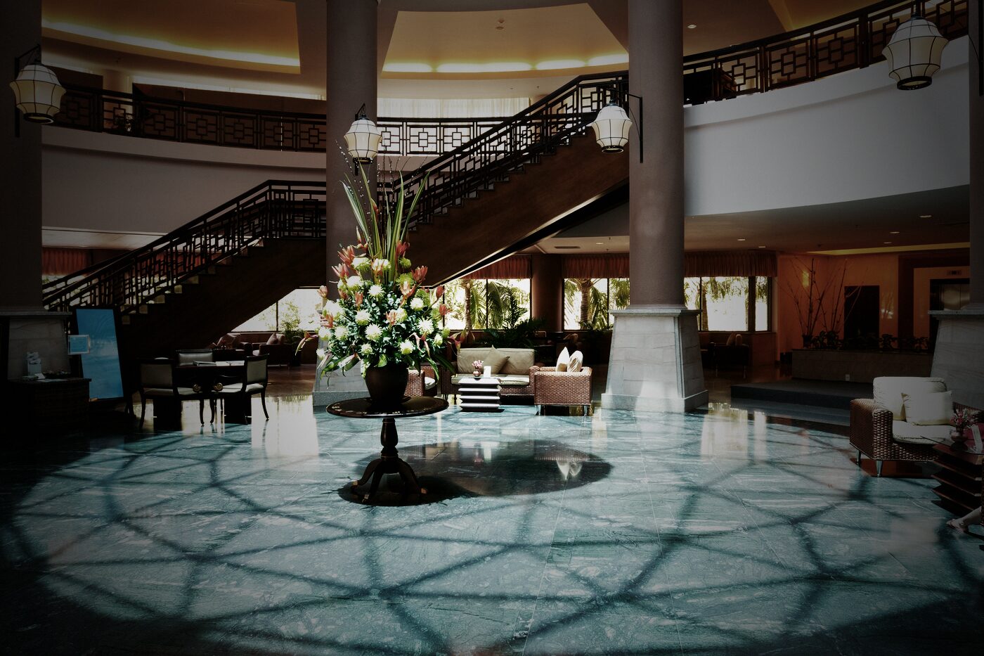 Hotellobby mit geschwungener Treppe und Blumenarrangement am Abend