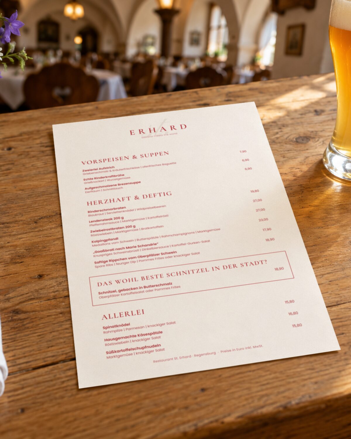 Speisekarte des Restaurants St. Erhard in Regensburg in Rot auf Creme mit Vorspeisen, bayerischen Hauptgerichten und einem hervorgehobenen Schnitzel, auf einem Holztisch im Gastraum