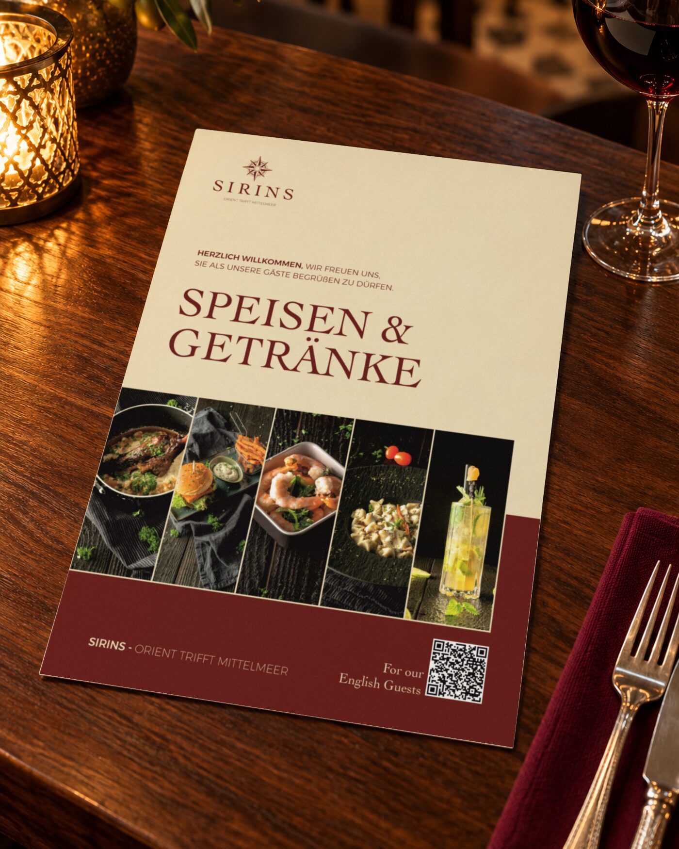 Titelseite der Speisekarte des Sirins Restaurants in Bad Säckingen mit dem Schriftzug Speisen und Getränke und fünf Foodfotos auf einem Nussbaumtisch im Kerzenlicht, daneben Rotwein und Besteck auf einer bordeauxroten Serviette